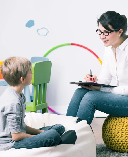 Woman sitting in front of a child with a clip board